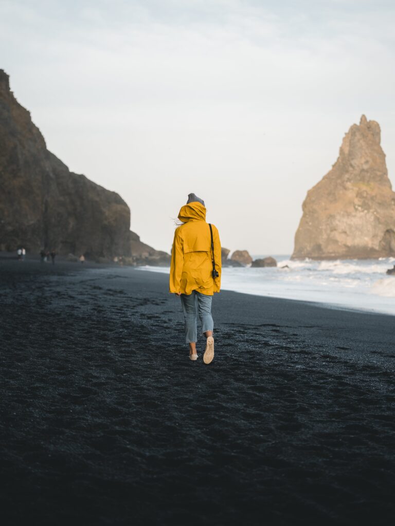 Back View of a Person Walking Along the Seashore